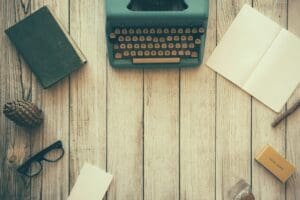 Vintage wooden desk with typewriter, book, and glasses - Life of Gini blog background