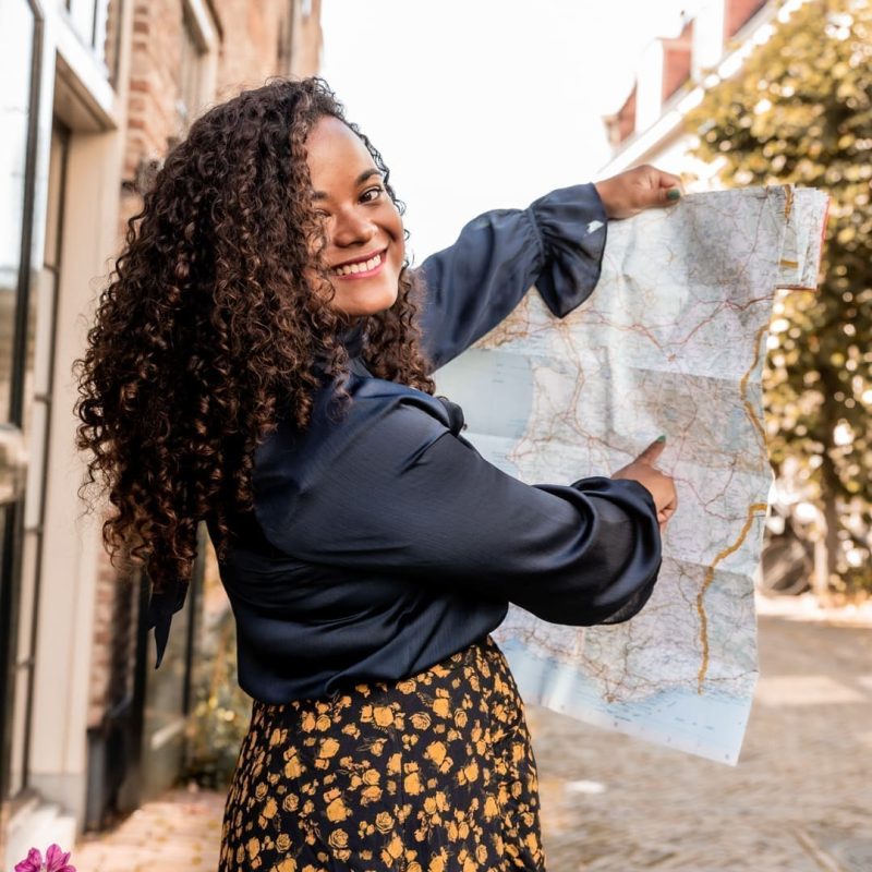 Virginia, travel specialist for solo travelers and travel buddies, holding a map and smiling